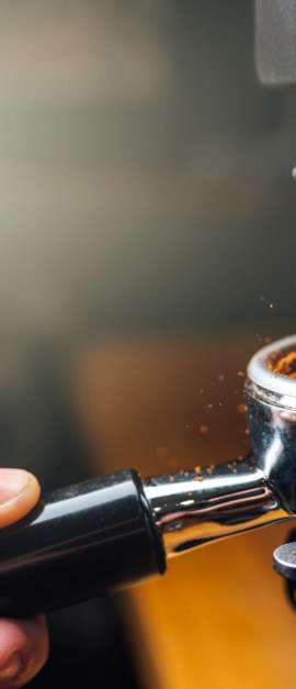 ground coffee pouring into a portafilter with a grinder, closeup